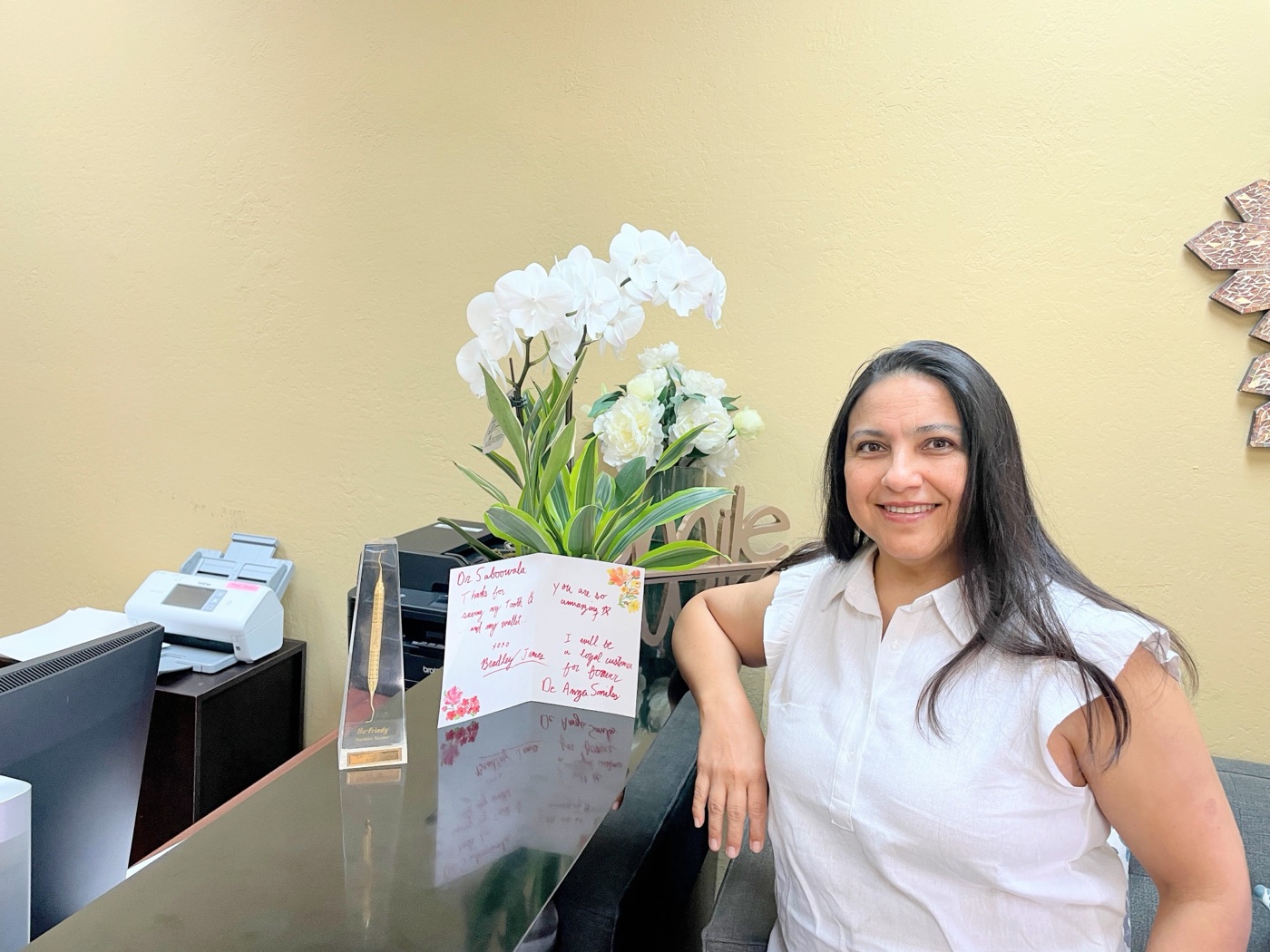 Dr. Insiya Saboowala at the De Anza Smiles front desk beside a patient's thank-you card